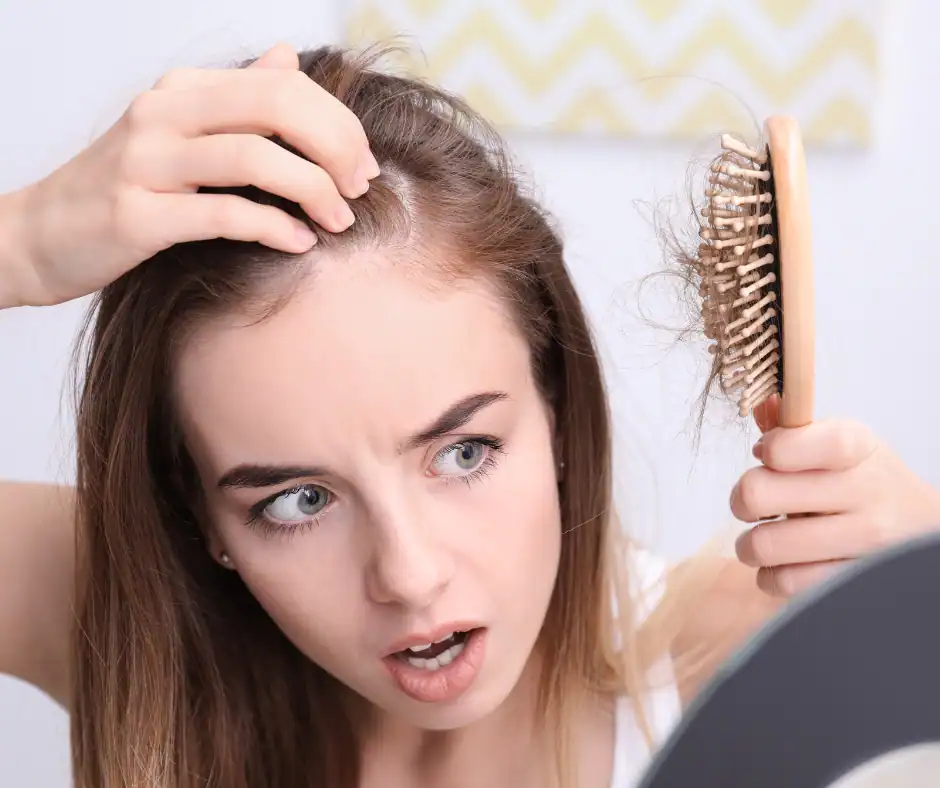 Woman with hair loss detangling her hair with a brush at Wigs by Opulence MN.