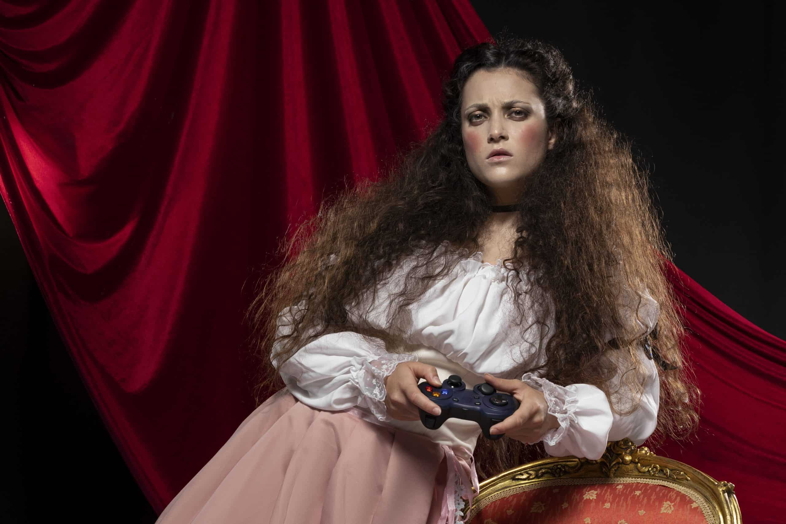 Woman with voluminous curly wig holding a game controller in a studio.